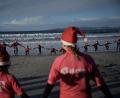 Bild: Adrián Irago/EUROPA PRESS/dpa
Mit Weihnachtsmannmützen verkleidete Menschen surfen während der „Papanoelada Surfera“ (Surfer-Nikolaus-Aktion) am Strand von Patos.