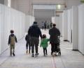 Archivbild: Boris Roessler/dpa
Eine Flüchtlingsfamilie geht durch die zu einer Massenunterkunft umfunktionierten Messehalle in Frankfurt.