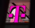Bild: Rainer Jensen/dpa/dpa-tmn
Ein Telekom-Logo strahlt in Magenta - für den Konzern sind die Behördenpläne eine gute Nachricht.