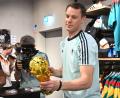 Bild: Federico Gambarini/dpa
Lächelnd signiert Manuel Neuer einen goldenen WM-Pokal.