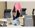 Bild: A7120 Bernd Wüstneck/dpa
Die Angeklagte betritt den Gerichtssaal mit rotem Aktendeckel vor dem Gesicht.
