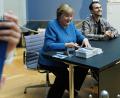 Bild: Carsten Koall/dpa
Merkel signiert Kunstpostkarten im Bode-Museum neben dem Maler ihres dort ausgestellten Porträts, Jérémie Queyras.