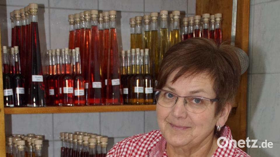 Likör von der Waldhimbeere: Emma Grosser präsentiert davon eine Flasche vor dem gefüllten Regal.