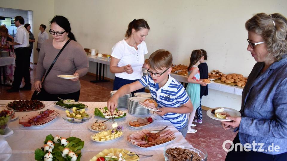 Die Kinder und ihre Eltern greifen beim Buffet beherzt zu.