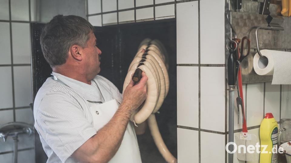 Matthias Schönberger jongliert die Fleischwürste in den Räucherofen.