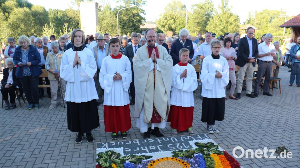 Pfarrer Heribert Stretz und die Ministranten vor dem Blumenteppich. rpp
