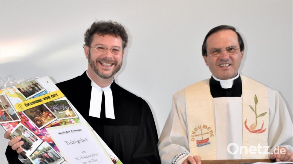 Pfarrer Bernhard Müller (rechts) überreicht an seinen evangelischen Kollegen Pfarrer Dr. André Fischer eine Tafel mit Bildern von gemeinsamen Vorträgen. Bild: rgr