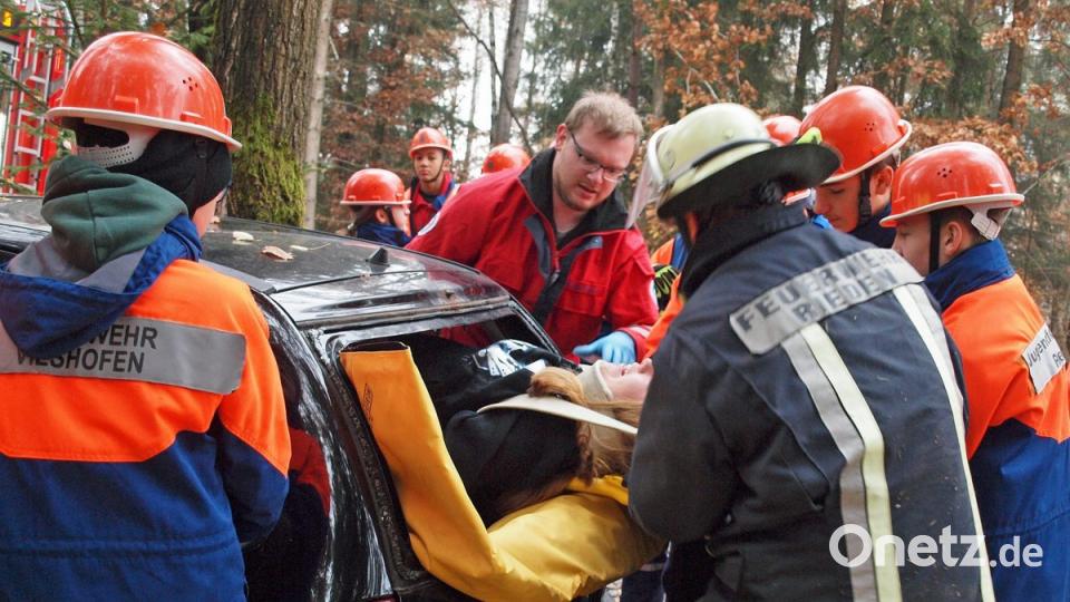 Unterstützt von einem Helfer vor Ort (Bildmitte) wurde die bewusstlose Beifahrerin mit Rettungsboa und Spineboard durch das entfernte Rückfenster geborgen. Bild: sön