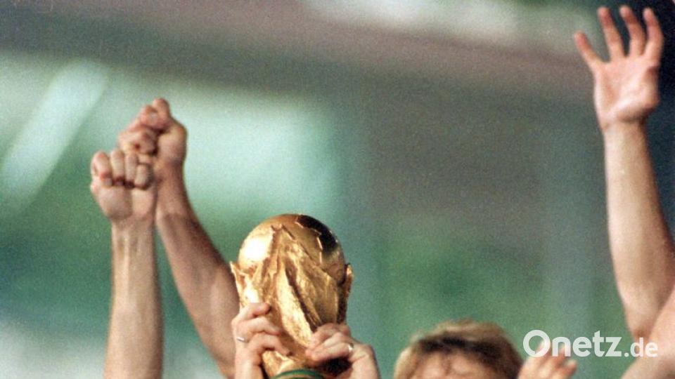 Mannschaftskapitän Lothar Matthäus hält bei der Siegerehrung der Fußball-Weltmeisterschaft am 08.07.1990 im Olympiastadion von Rom triumphierend den WM-Pokal in die Höhe. Hinter ihm jubelt Torjäger Jürgen Klinsmann. Bild: Frank Kleefeldt/dpa