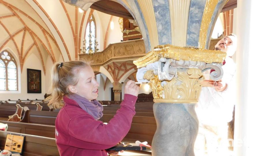 Mit ruhiger Hand und viel Ausdauer verziert Kirchenmalerin Hannah Rödig den Unterbau der Kanzel mit Blattgold. Bild: hai