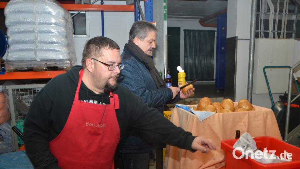 Die Ankunft der neuen Drehleiter wird mit Bratwurstsemmeln gefeiert. Harald Bäumler und Bürgermeister Andreas Wutzlhofer arbeiten Hand in Hand. Bild: dob