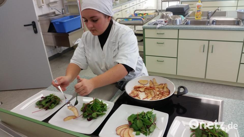 Vinaigrette über den Blattsalat verteilen, mit gerösteten Nüssen garnieren und Apfelspalten am Teller auflegen. Bild: Portner