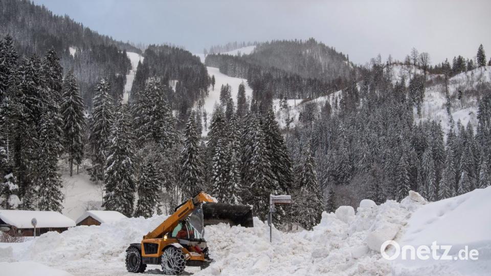 Mithilfe eines Teleskop-Radladers werden Rettungswege am Spitzingsee freigeräumt. Bild:  Lino Mirgeler/dpa