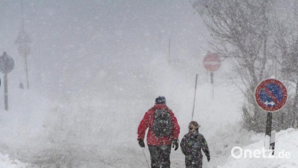 Eine Frau und ein Kind gehen in St. Englmar mit einem Schlitten auf einer verschneiten Straße. Bild: Armin Weigel/dpa