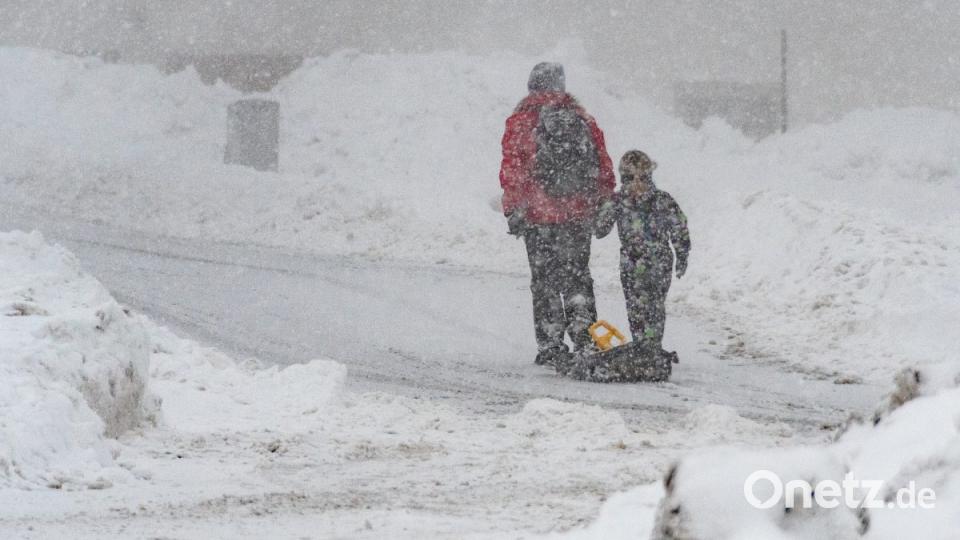 Eine Frau und ein Kind gehenin St. Englmar mit einem Schlitten auf einer verschneiten Straße. Bild: :Armin Weigel/dpa