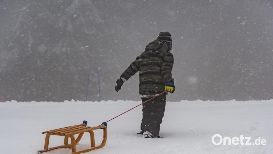Ein Junge zieht seinen Schlitten in Sankt Englmar auf einen Berg. Bild: Armin Weigel/dpa