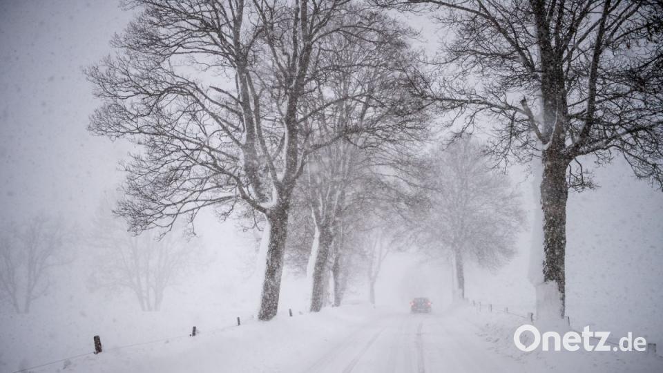 Ein Auto fährt in Warngau über eine Schnee verwehte Landstraße. Der Landkreis Miesbach hat wegen starker Schneefälle Katastrophenalarm ausgelöst. Bild: Lino Mirgeler/dpa