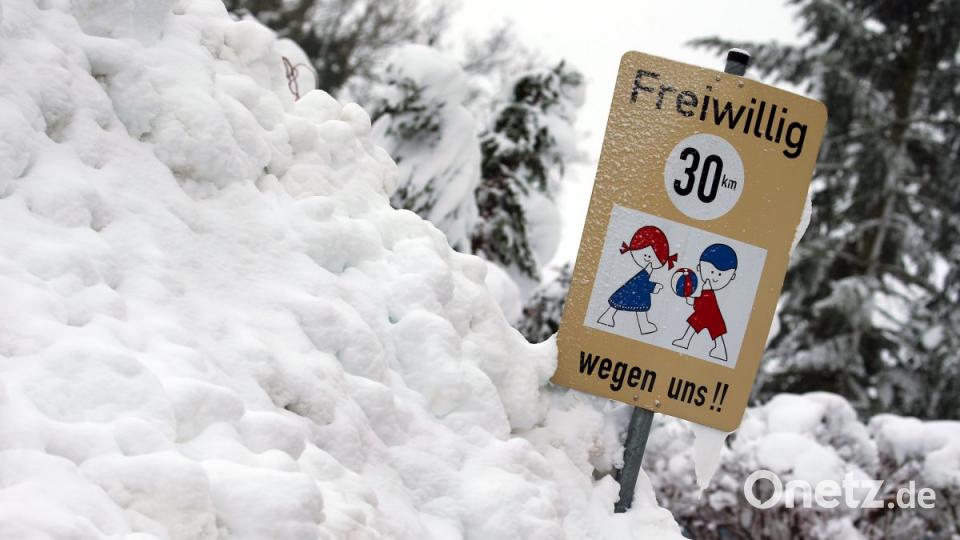 Ein Hinweisschild auf spielende Kinder steht in einem Schneehaufen. Bild: Karl-Josef Hildenbrand/dpa