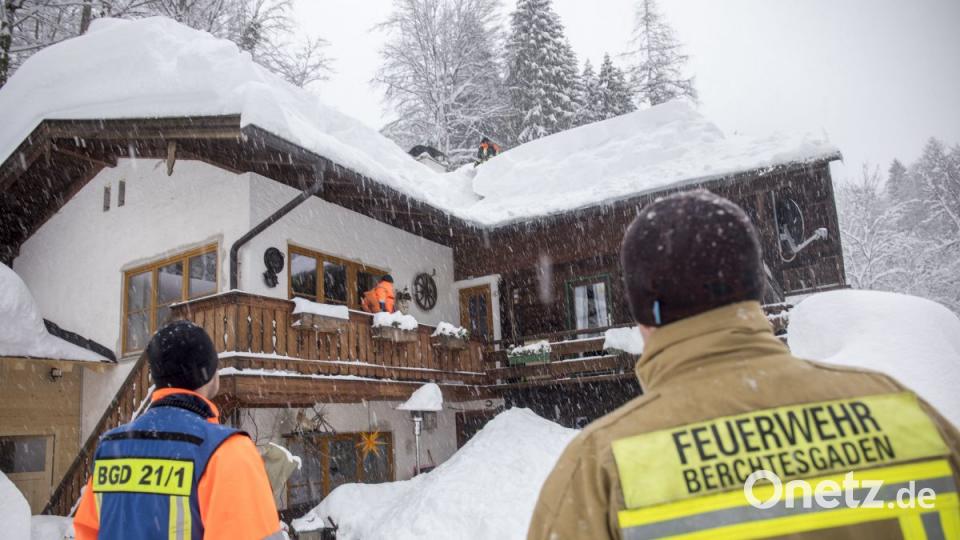 Feuerwehrmänner schaufeln in Buchenhöhe Schnee vom Dach eines Hauses. Nach starkem Schneefall sitzen bei Berchtesgaden rund 350 Menschen fest. Bild: Bernd März/dpa