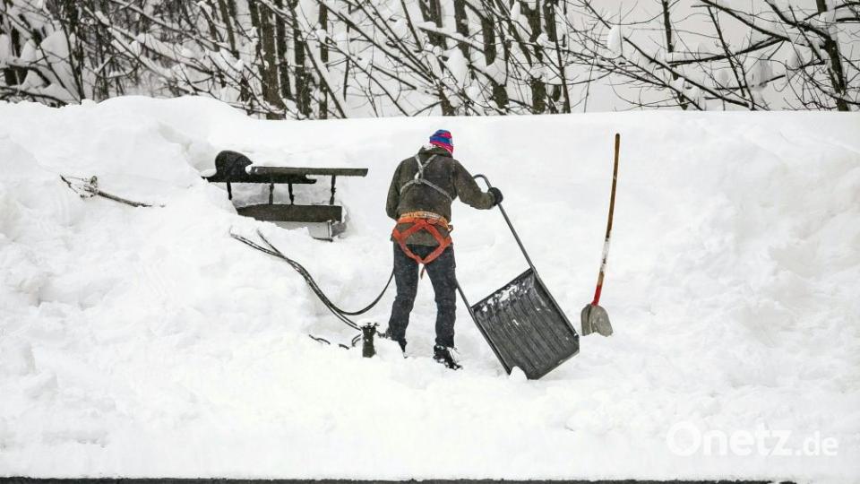 Ein Mann befreit ein Dach von der Schneelast in Saalbach. Immer mehr Orte sind aufgrund der sehr großen Lawinengefahr nicht mehr erreichbar - darunter auch der Ort Galtür in Tirol. Bild: Expa/Jfk/APA/dpa