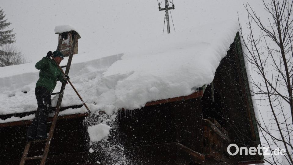 Ein Mann befreit in Jachenau sein Hausdach vom Schnee. Bild: Angelika Warmuth/dpa