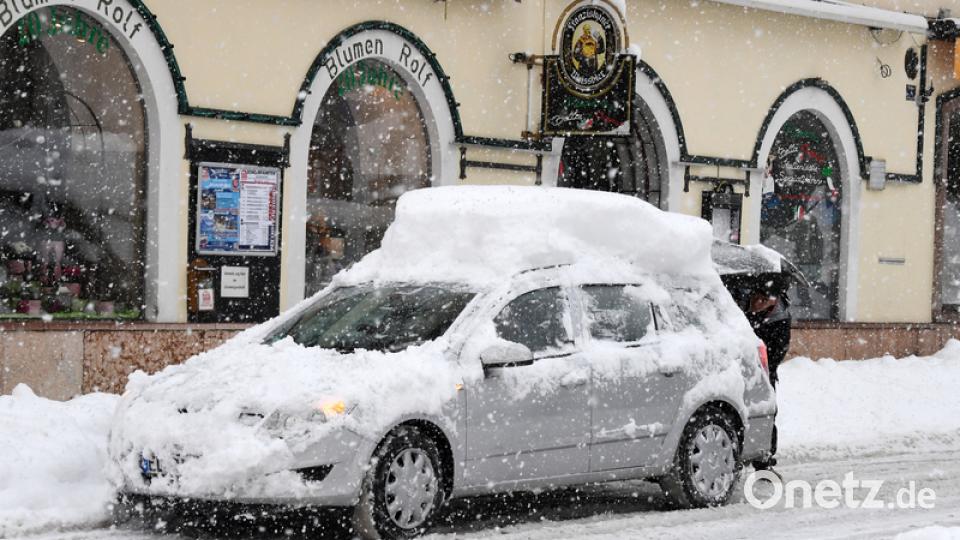 Berchtesgaden: Ein Mann steht am Kofferraum seines schneebedeckten Autos. Bild: Tobias Hase/dpa