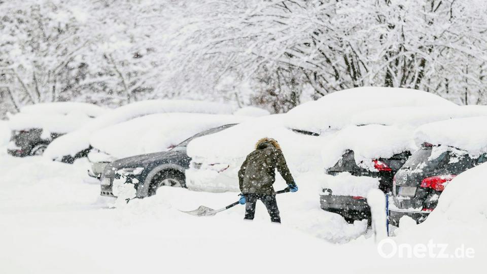 Ein Mann schaufelt am Mittwoch im österreichischen Saalbach sein Auto auf einem Parkplatz aus. Bild:  Expa/Jfk/APA/dpa