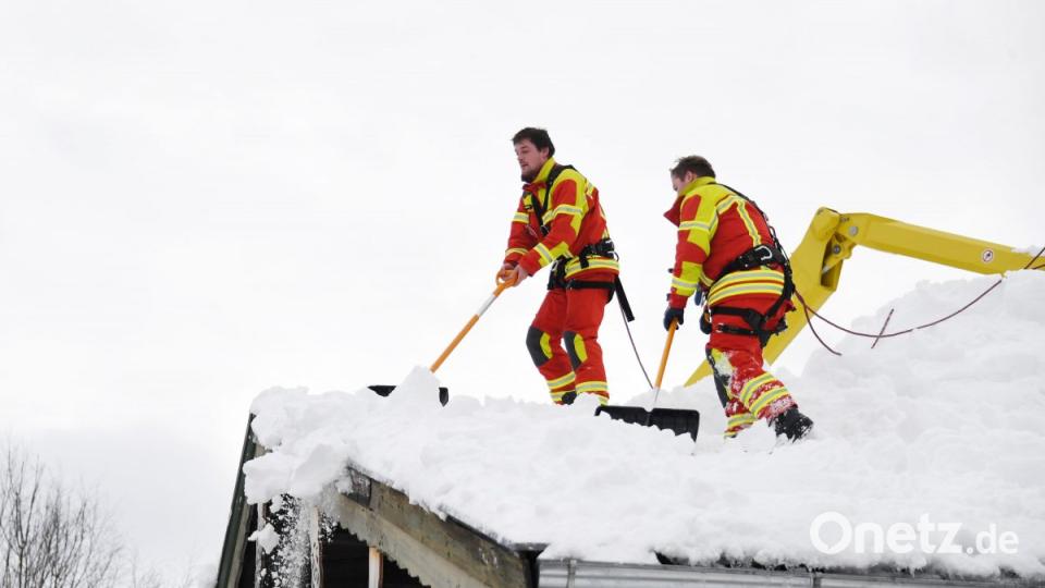 Inzell: Feuerwehrleute räumen den Schnee vom Dach eines Hauses. Bild: Tobias Hase/dpa