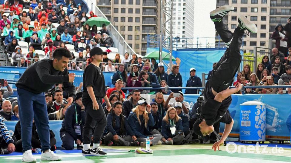 &quot;Broly&quot; (links) aus Argentinien und &quot;Lexy&quot; (Mitte) aus Italien beobachten &quot;B4&quot; (rechts) aus Vietnam beim Finale von Breakdance bei den Olympischen Jugendspielen in Buenos Aires 2018. Im Jahr 2024 soll Breakdance bei den Olympischen Sommerspielen in Paris eine offizielle Disziplin werden. Bild: Fabian Ramella/dpa