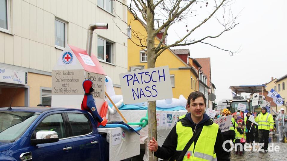 „Schwimmbahnen statt Schießbahnen“ fordert die Auerbacher Wasserwacht. Das Schild „Patschnass“ hat an diesem regnerischen Faschingsdienstag programmatischen Charakter. Bild: jma