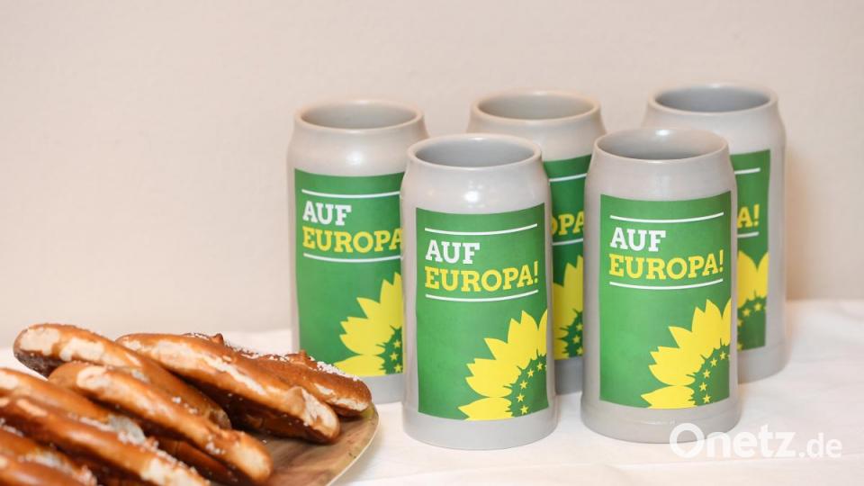 Bierkrüge mit der Aufschrift "Auf Europa!" stehen beim politischen Aschermittwoch von Bündnis 90/Die Grünen in München neben Brezen. Bild: Tobias Hase/dpa