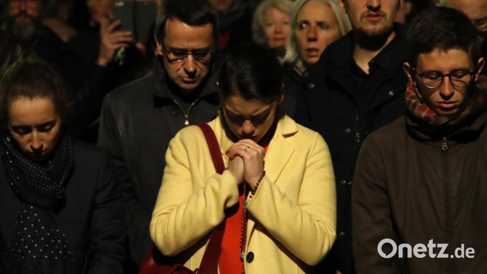 Paris: Menschen beten, während die Kathedrale Notre Dame in Paris brennt. Bild: Christophe Ena/AP/dpa
