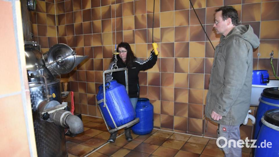 Mit der Hilfe eines Flaschenzuges befördert Birgit Schlötzer die blauen Fässer mit der Maische ein Stück weit nach oben, um den Inhalt in den Brennapparat zu bekommen. Bild: lue