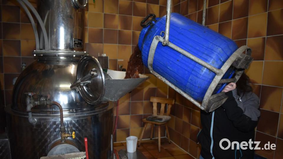 Mit der Hilfe eines Flaschenzuges befördert Birgit Schlötzer die blauen Fässer mit der Maische ein Stück weit nach oben, um den Inhalt in den Brennapparat zu bekommen. Bild: lue