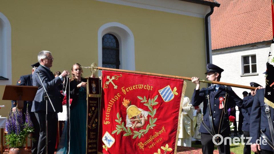 Schrimherr Bürgermeister Richard Tischler heftet das Erinnerungsband der Stadt Pfreimd an die Fahne des Jubelvereins. Bild: bnr