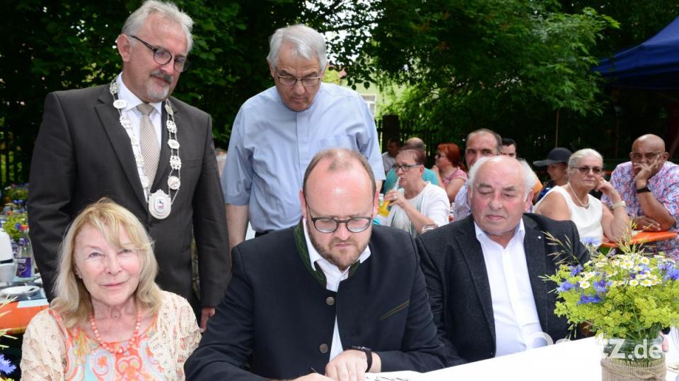 Landrat Andreas Meier trägt sich ins Goldene Buch der Gemeinde Püchersreuth ein. Rita Kielhorn (links) hatte sich bereits im Buch verewigt. Bürgermeister Rudolf Schopper und Pfarrer Manfred Wundlechner schauen dem Landkreischef über die Schulter, Altbürgermeister Lorenz Enslein (rechts) liest den Eintrag des Landrats. Bild: bey