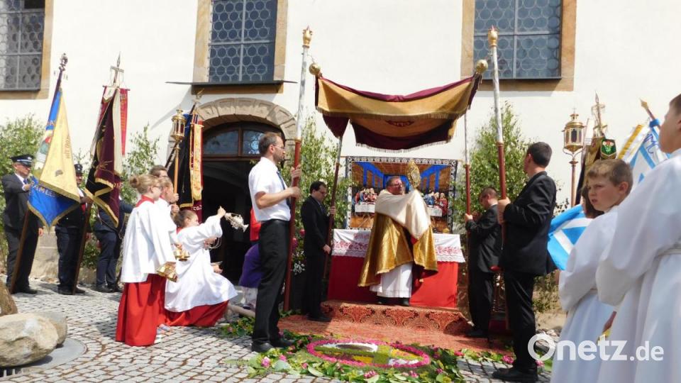 Pfarrer Sven Grillmeier zieht mit dem Allerheiligsten durch die Straßen und macht an einem geschmückten Altar Halt.