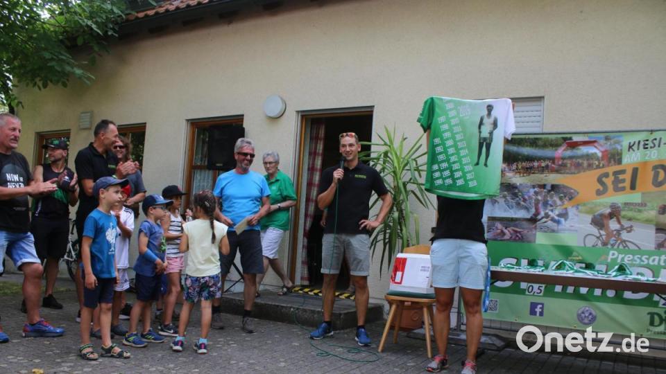 Vorsitzender Siegfried Rauch wird zu seinem 60. Geburtstag mit einem T-Shirt, auf dem Bild seiner ersten Triathlon-Teilnahme abgedruckt ist, überrascht. Bild: sne