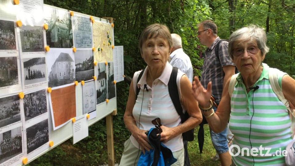 Ingrid Blodig (links) und Edeltraud Gleißner lassen in Lutzmannstein Erinnerungen an ihre Kindheit aufleben. Vor einer Stellwand mit alten Fotos erzählen die Schwestern, wie es damals war in dem kleinen Ort. Bild: Unger, Heike