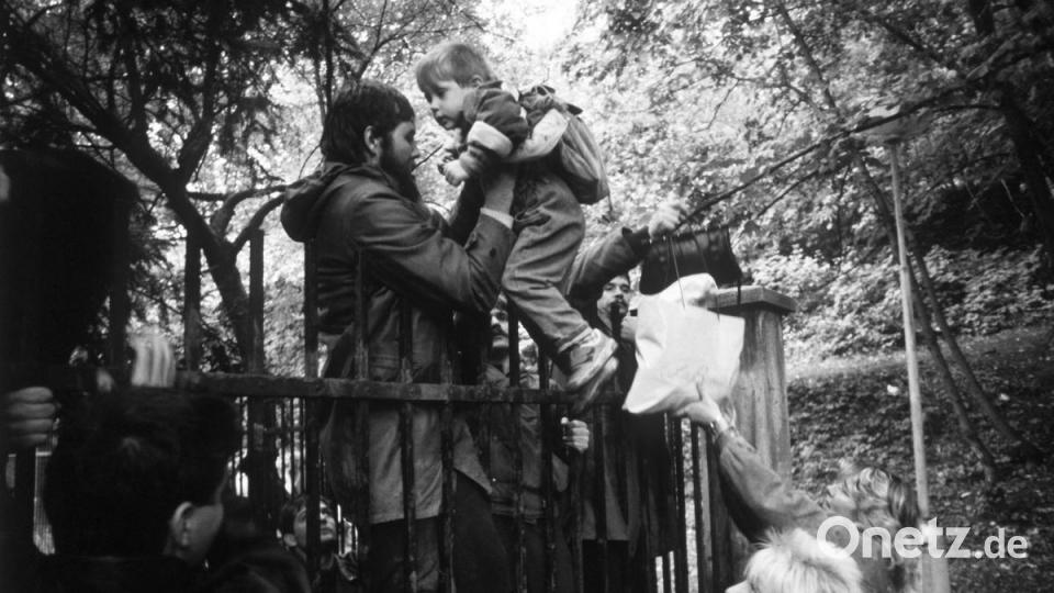DDR-Bürger klettern am 29 September 1989 mit ihren Kindern über den Zaun der bundesdeutschen Botschaft in der tschechoslowakischen Hauptstadt Prag. Archivbild: Reinhard Kemmether/dpa