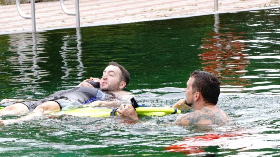 Eine schwimmende Trage wird unter die zu rettende Person geschoben, was auch der Übung bedarf. Bild: bkr