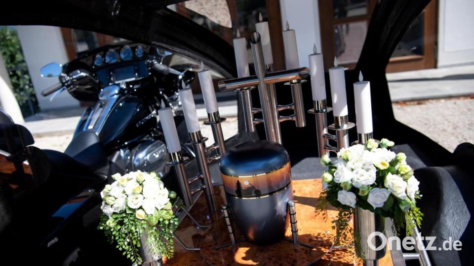 Eine Urne steht im Beiwagen von einem Bestattungsmotorrad, einer umgebauten Harley-Davidson, auf einem Friedhof. Bild: Sven Hoppe/dpa