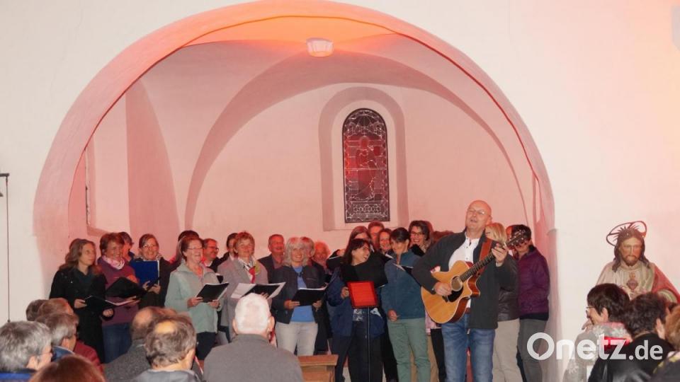 Voll besetzt war die in Rot getauchte Friedhofskirche, als der Chor „Contigo“ Geistliche Lieder zu Hoffnung und Trauer vortrug. Bild: weu