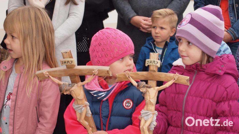 Pfarrer Gottfried Schubach übergab Kreuze an zwei Kinder für die Gruppenräume. Bild: sön