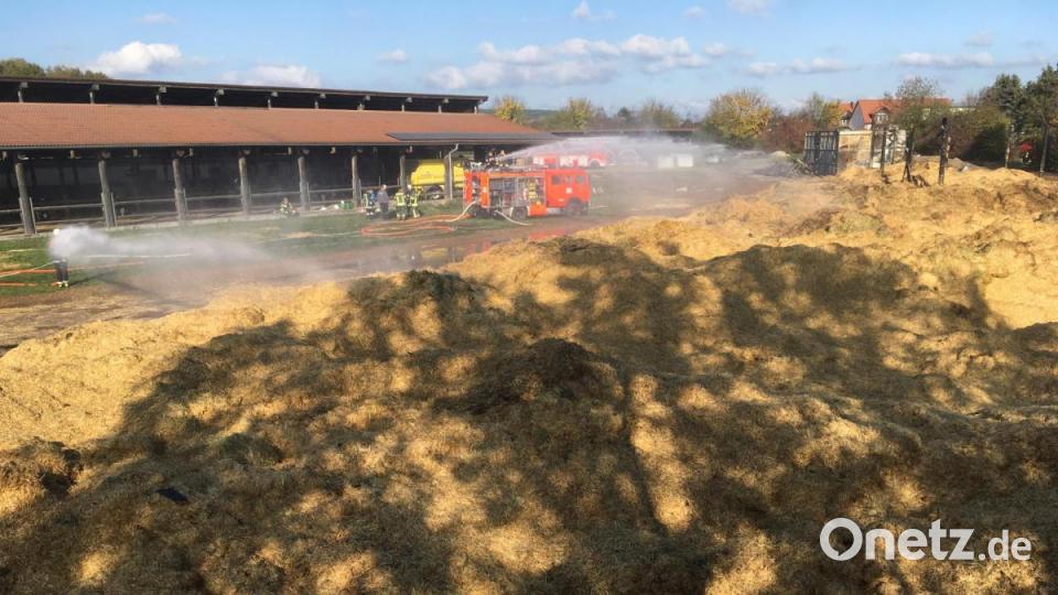 Der nächste Morgen in Rothenstadt: Die Feuerwehr löscht noch immer Glutnester im ausgebreiteten Stroh ab. Von der Scheune hinten rechts ist nicht mehr viel übrig. Bild: Gustl Beer