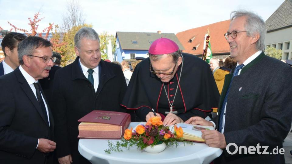 Weihbischof Dr. Josef Graf trug sich beim Stehempfang vor dem Gotteshaus ins Goldene Buch des Landkreises und der Gemeinde Ursensollen ein, das jeweils Landrat Richard Reisinger (Zweiter von links) und Bürgermeister Franz Mädler (rechts) vorlegten. Bild: dob