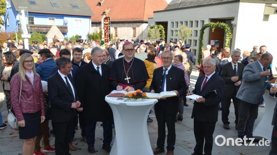 Weihbischof Dr. Josef Graf trug sich beim Stehempfang vor dem Gotteshaus ins Goldene Buch des Landkreises und der Gemeinde Ursensollen ein, das jeweils Landrat Richard Reisinger (Dritter von links) und Bürgermeister Franz Mädler (Zweiter von rechts) vorlegten. Pfarrgemeinderatssprecher Johann Schmaußer (rechts) brachte ebenfalls ein Gästebuch mit. Bild: dob