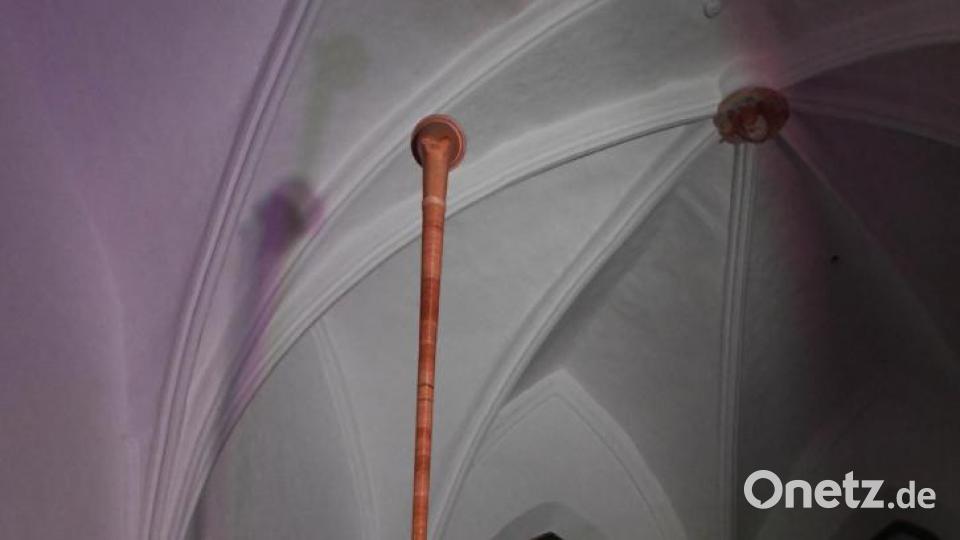 Sepp Schabernack balanciert sein mehrere Meter langes Alphorn über Kopf und spielt darauf. Bild: Freya Stoeckl