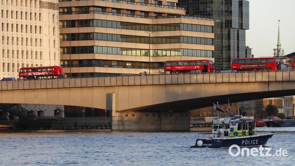 Ein Polizeiboot fährt auf der Themse an der London Bridge vorbei, auf der leere Busse abgestellt sind. Bild: Frank Augstein/AP/dpa
