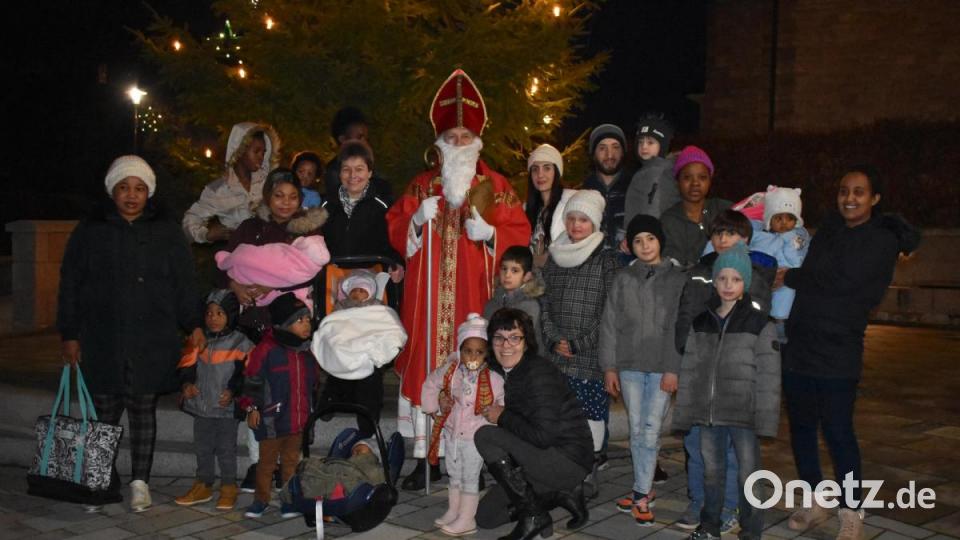 Anita Heindl (Mitte knieend) hat als ehrenamtliche Helferin eine Weihnachtsaktion für Flüchtlingskinder geplant. Dafür sammelte sie Spenden und überreicht nun in Neusorg 23 voll bepackte Tüten an die Kleinen oder ihre Mütter. Der heilige Nikolaus steht ihr mit Rat und Tat zur Seite. Bild: lue